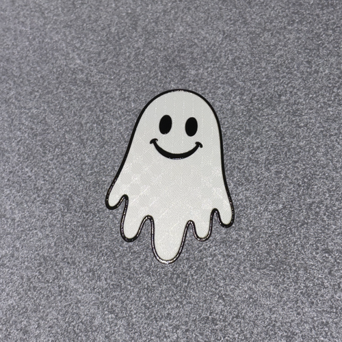 A small embroidered ghost patch with a smiling face, outlined in black, placed on a textured gray fabric background.