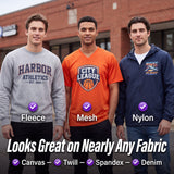Three men standing outdoors in front of a brick building, each wearing a different color athletic-style graphic top: a gray sweatshirt labeled Fleece, an orange mesh V-neck labeled Mesh, and a navy nylon zip jacket labeled Nylon. Large text at the bottom reads 'Looks Great on Nearly Any Fabric' with fabric type labels underneath.